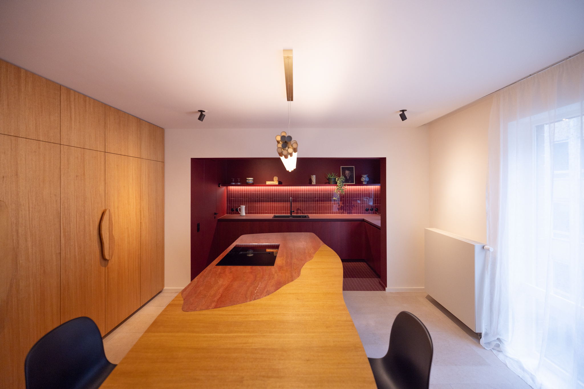 cuisine design haut de gamme, carrelage bordeaux, fenix rosso jaipur, travertin, îlot organique, placage bois