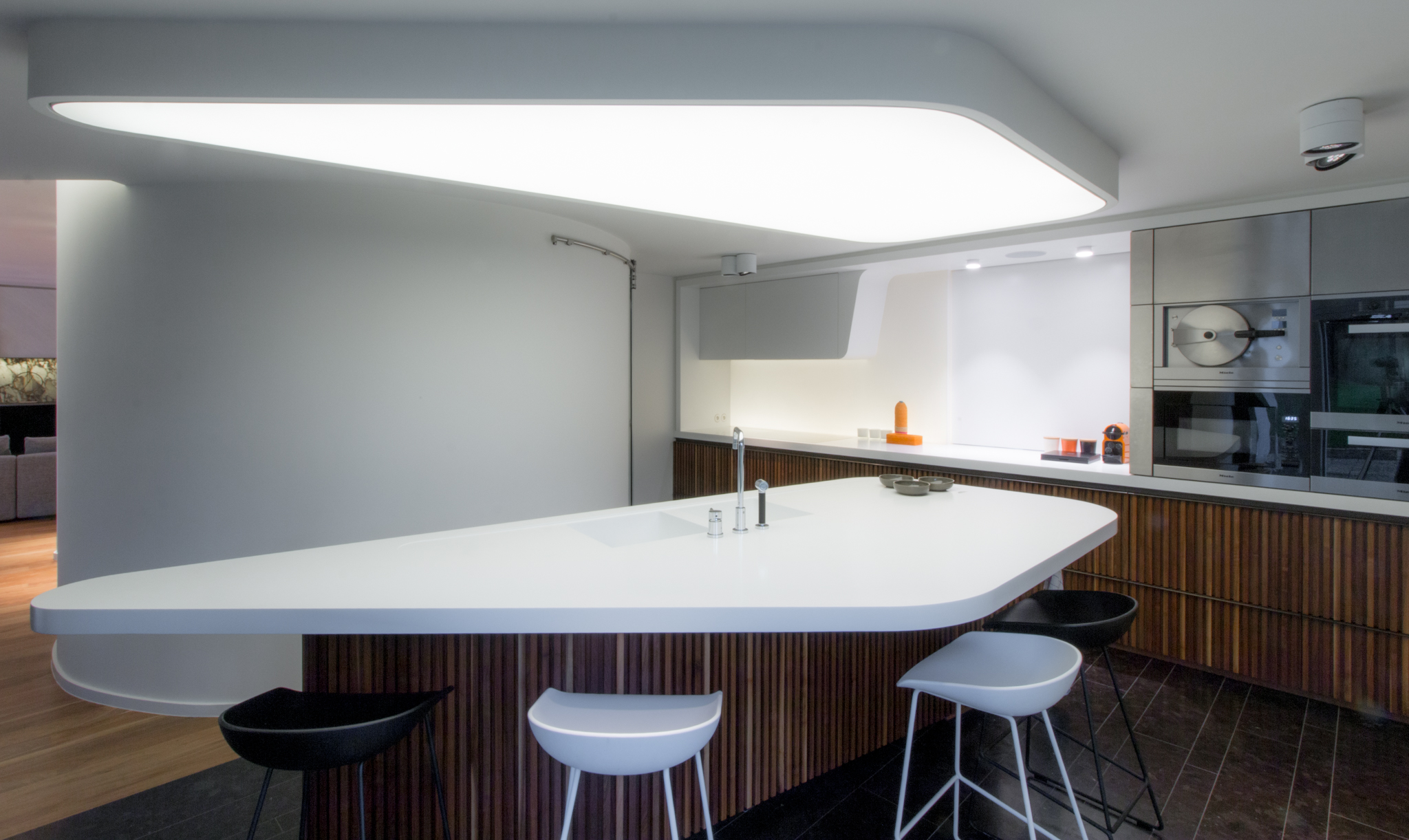 Cuisine moderne bois et plan de travail Corian avec îlot triangulaire dans une villa
