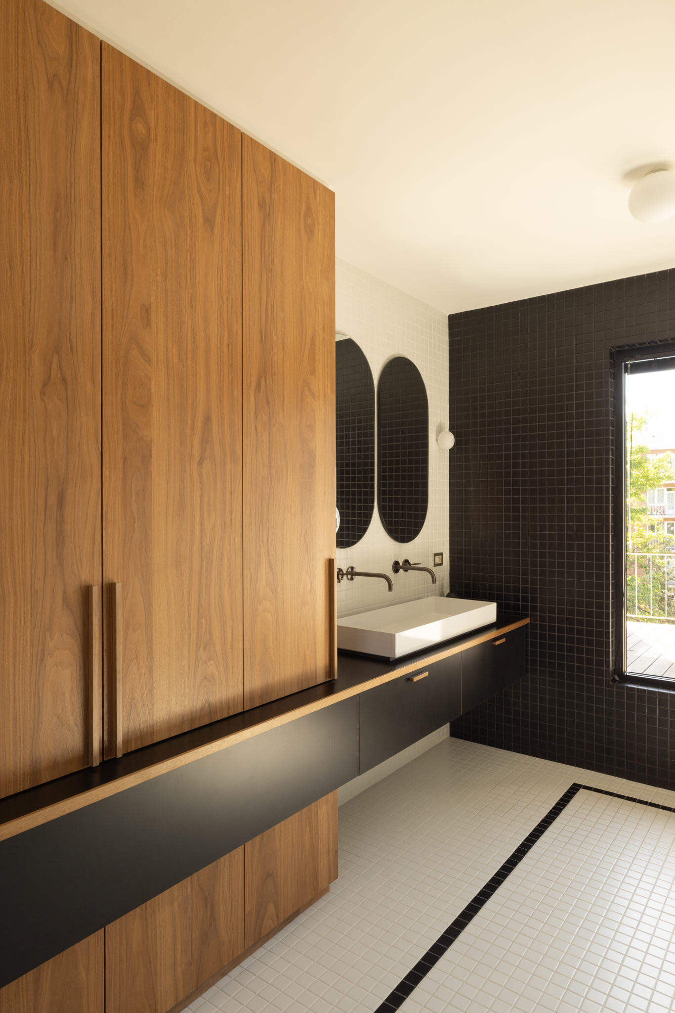 Salle de bain avec carrelage noir et blanc en petit format, inspiré des années 30, double vasque et menuiserie sur mesure intégrée