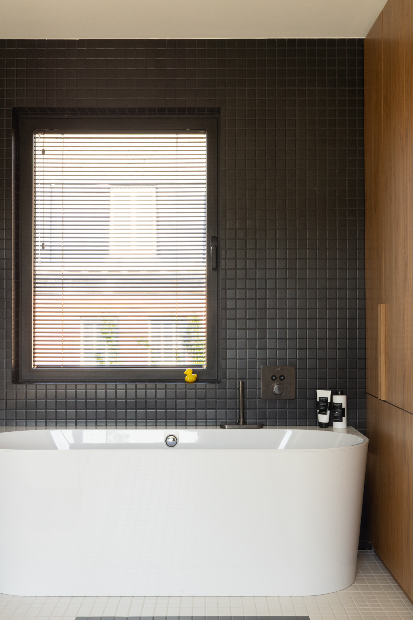 Salle de bain avec carrelage noir et blanc en petit format, inspiré des années 30, baignoire et menuiserie sur mesure intégrée