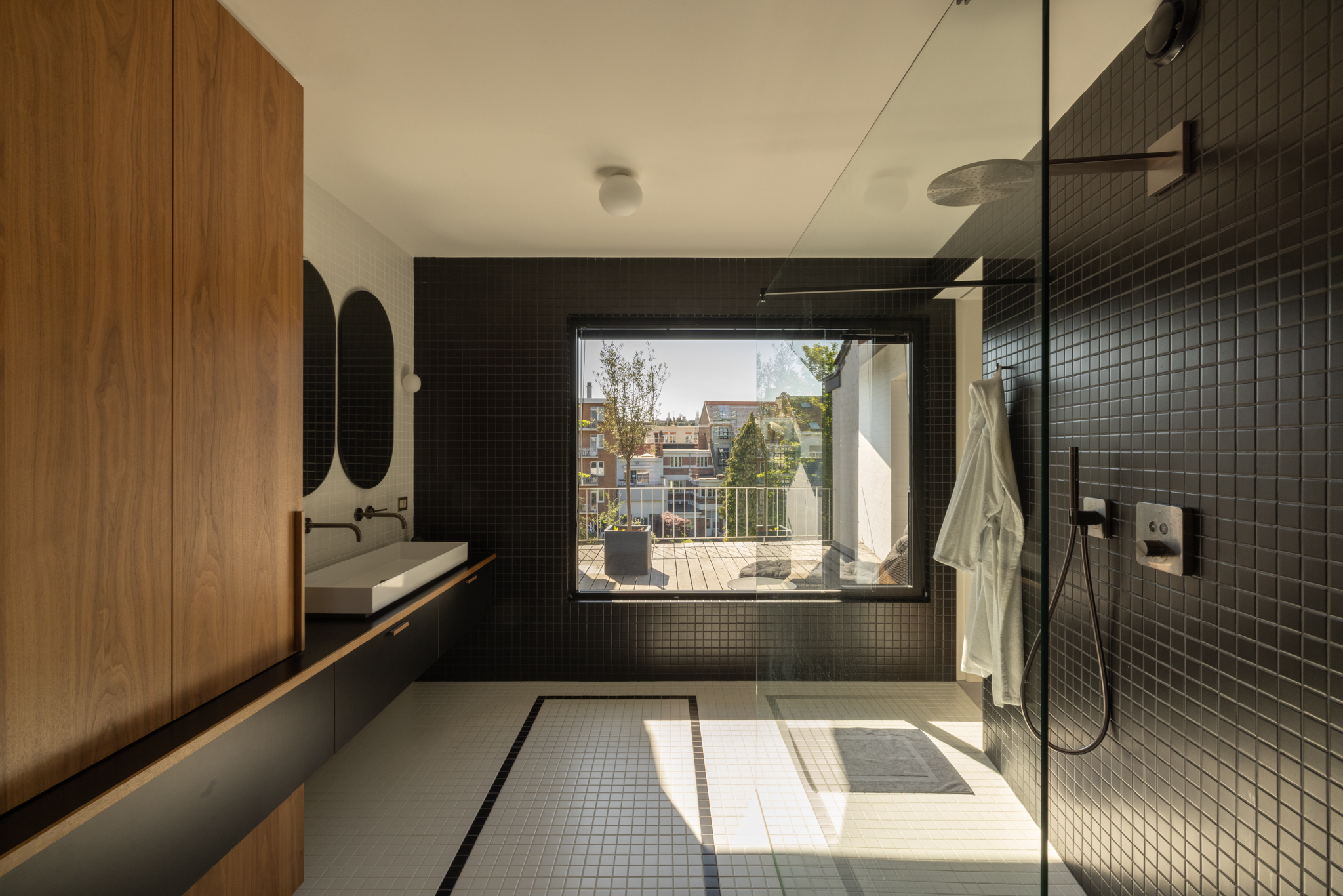 Salle de bain avec carrelage noir et blanc en petit format, inspiré des motifs de tapis des années 30, et menuiserie sur mesure intégrée