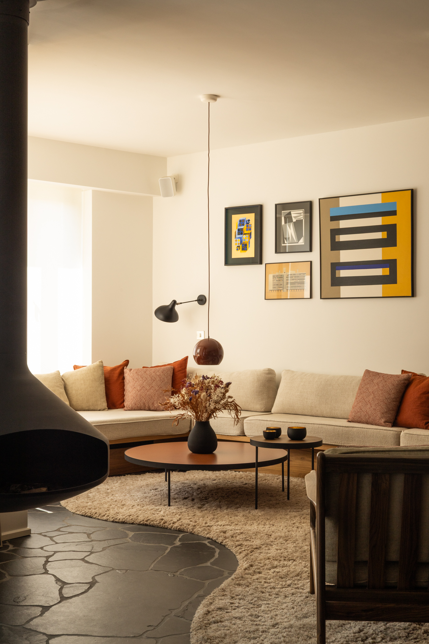 salon rénové dans une maison bruxelloise des années 30, avec sols en pierre naturelle sombre et cheminée suspendue